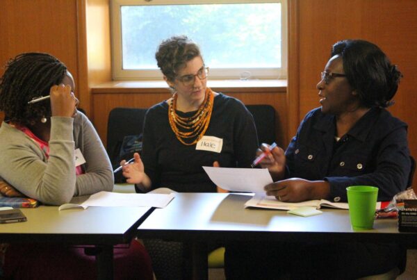 Three people discuss around a table