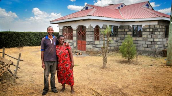 couple stands outside their home in Kenya